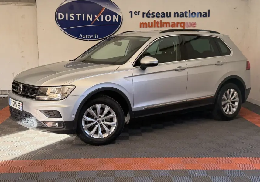 Volkswagen Tiguan gris clair vue de profil droit en intérieur avec jantes alliage et barres de toit noires.