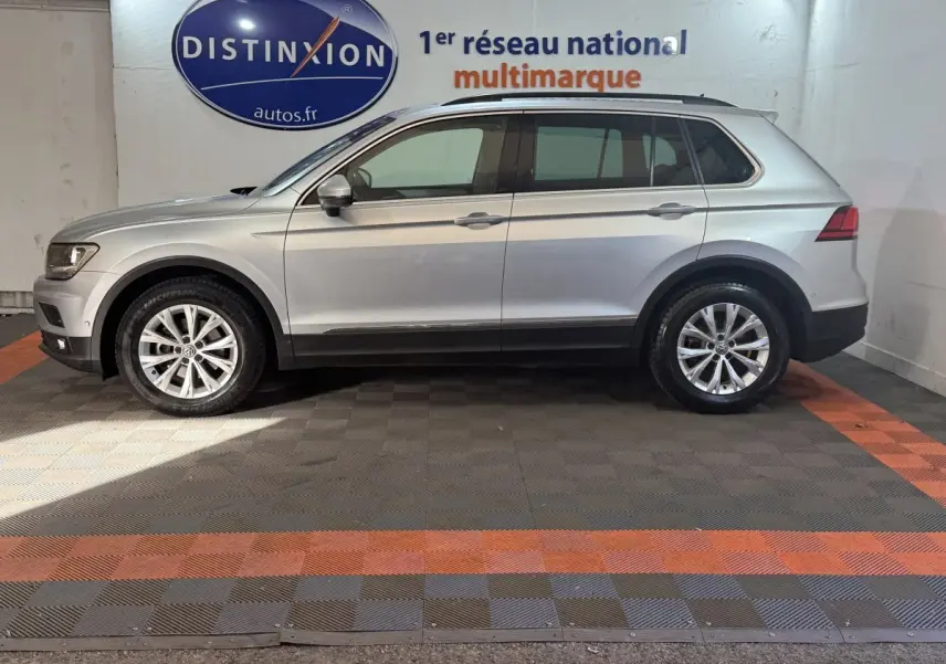 Profil droit d’un Volkswagen Tiguan gris clair 2020, SUV compact avec jantes alliage et barres de toit noires.