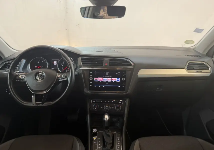 Vue intérieure avant du Volkswagen Tiguan 2020, tableau de bord noir avec écran tactile et volant cuir multifonctions.