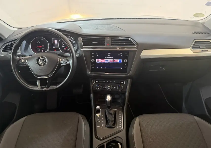 Vue intérieure avant du Volkswagen Tiguan 2020, tableau de bord avec volant cuir multifonctions et écran tactile central.