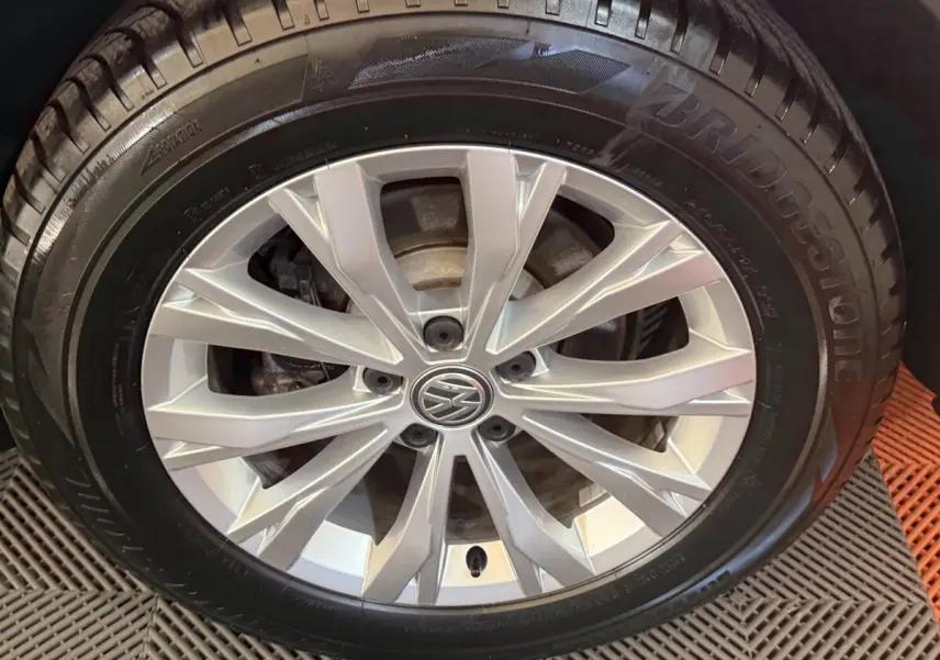 Gros plan sur la roue avant droite avec jante argentée et logo Volkswagen au centre, pneu Bridgestone noir.