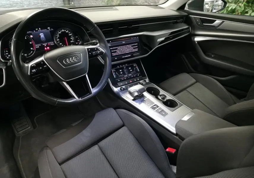 Vue intérieure côté conducteur de l'Audi A6 Avant 2022 avec tableau de bord numérique et sellerie noire.