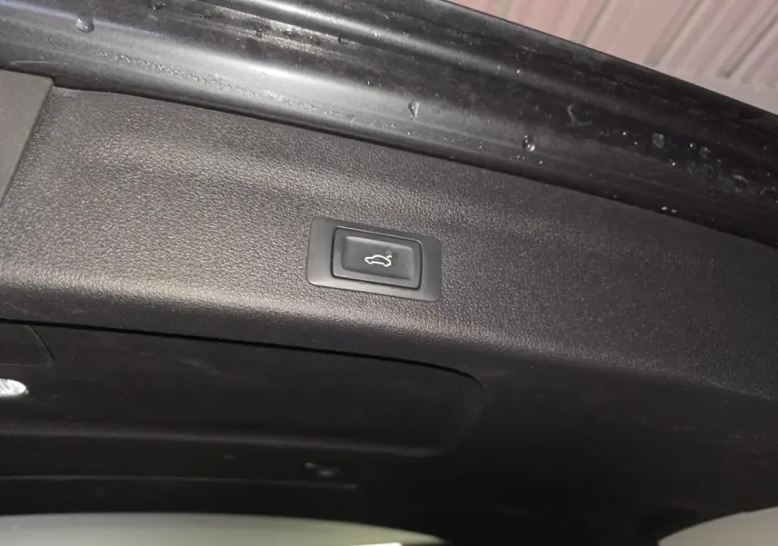 Bouton d'ouverture électrique du hayon sur la partie intérieure du coffre d'une Audi A6 gris 2022 S line.
