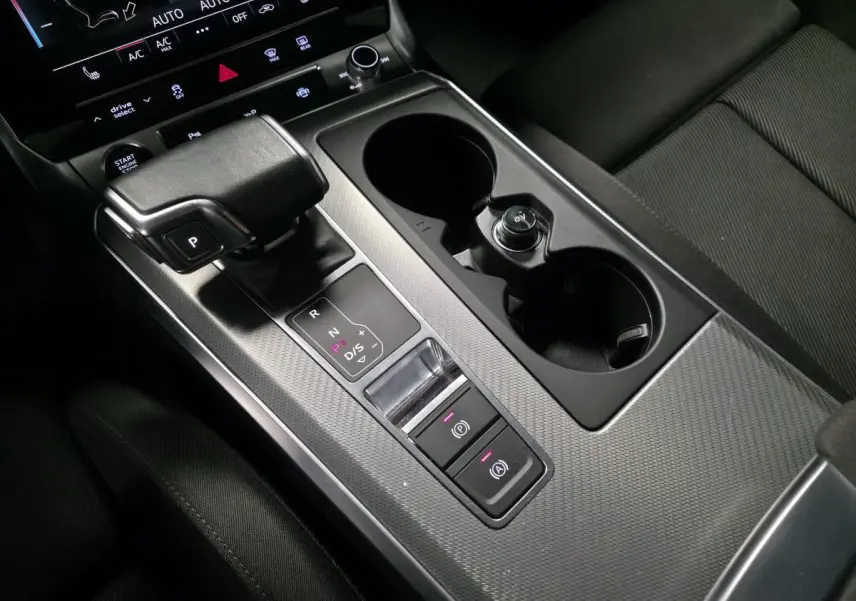Gros plan sur la console centrale noire de l'Audi A6 Avant 2.0 TDI 2022 avec levier de vitesses et porte-gobelets.