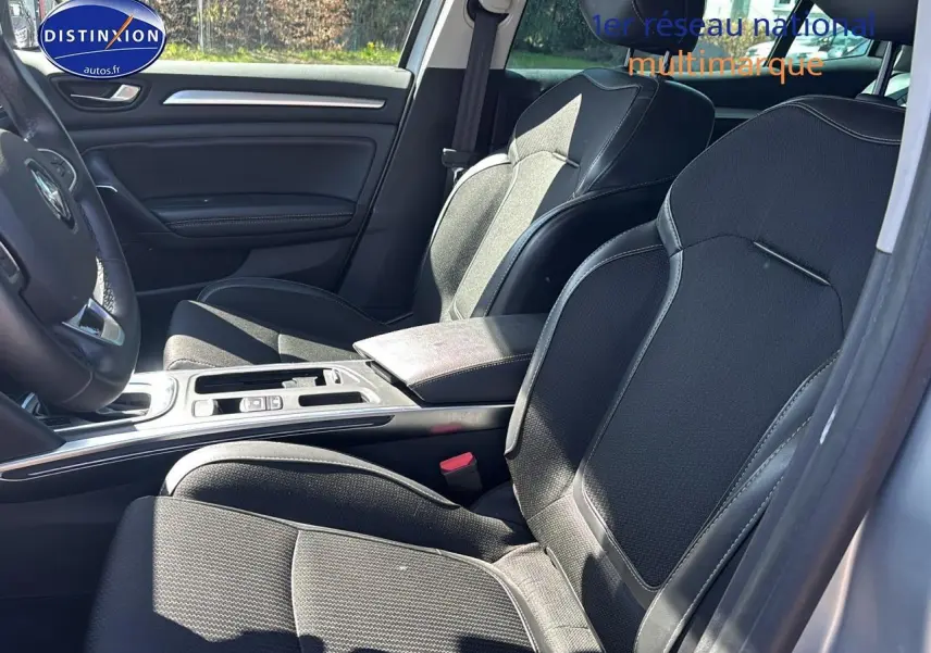 Vue intérieure côté conducteur de la Renault Mégane IV 1.5 Blue dCi 115 Techno EDC avec sièges noirs et console centrale.