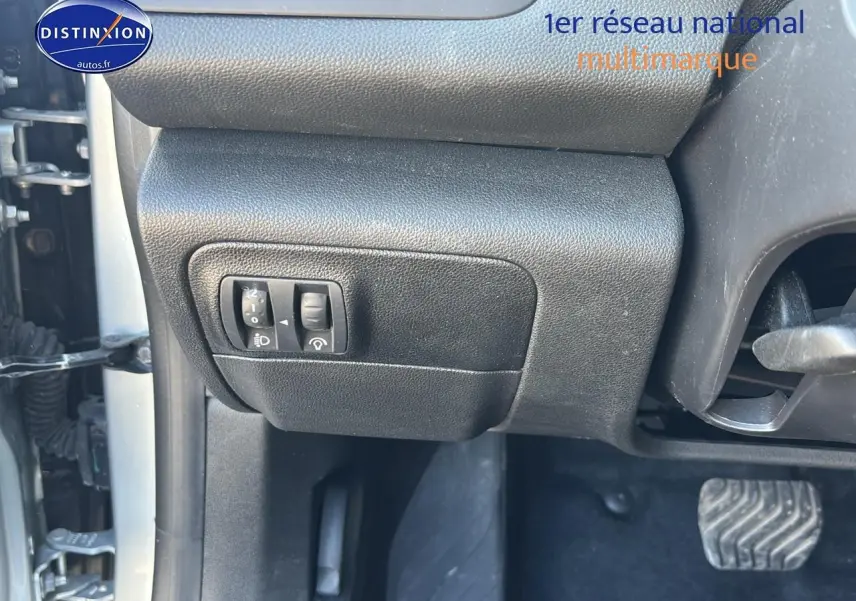 Détail intérieur côté gauche avec commandes de réglage des phares et pédale d’embrayage visible sur Renault Mégane IV gris Highland.