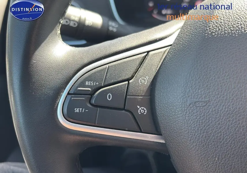 Gros plan sur les commandes de régulateur de vitesse au volant en similicuir noir de la Renault Mégane IV gris Highland.
