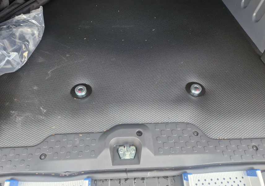 Vue rapprochée du plancher noir antidérapant du coffre du Renault Trafic Combi gris, avec deux plots de fixation pour fauteuil roulant.