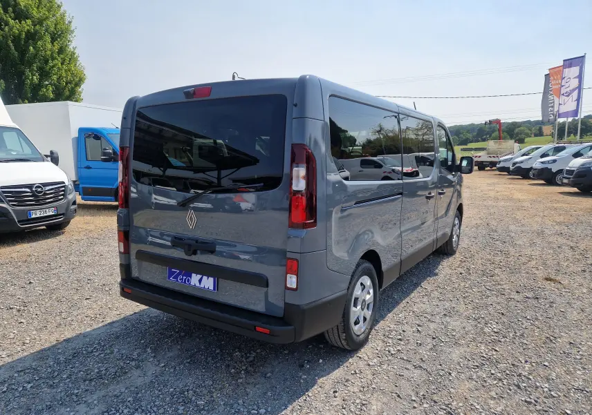 Vue 3/4 arrière droite d’un Renault Trafic Combi gris urbain, avec vitres teintées et hayon fermé sur parking.