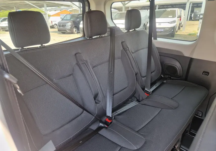 Vue intérieure latérale droite des sièges arrière noirs du Renault Trafic Combi 2026, avec ceintures de sécurité visibles.