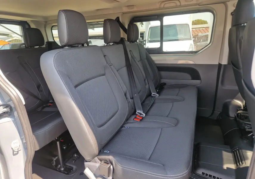 Vue intérieure côté droit du Renault Trafic Combi 2026 gris urbain, montrant les sièges passagers en tissu noir avec ceintures de sécurité.