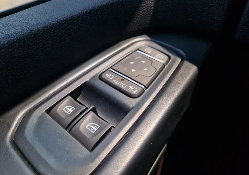 Gros plan sur les commandes électriques des vitres et rétroviseurs dans l’habitacle noir du Renault Trafic Combi gris urbain.