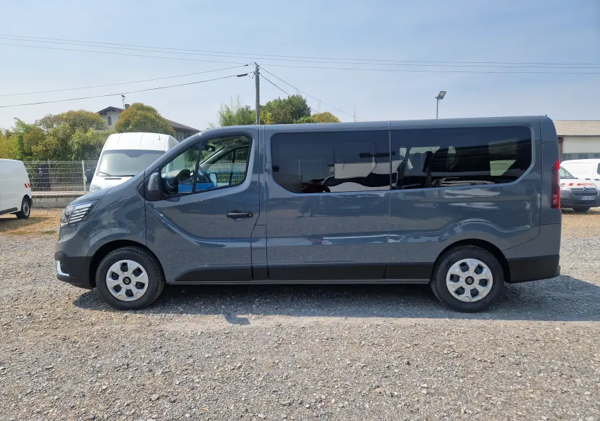 Profil côté gauche d’un Renault Trafic Combi gris urbain 2026, avec vitres teintées et porte coulissante visible.