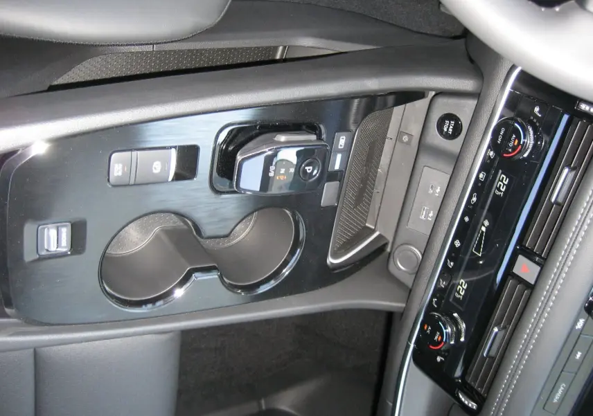 Vue rapprochée de la console centrale noire du Nissan X-TRAIL blanc nacré, avec commandes de boîte auto et climatisation digitale.