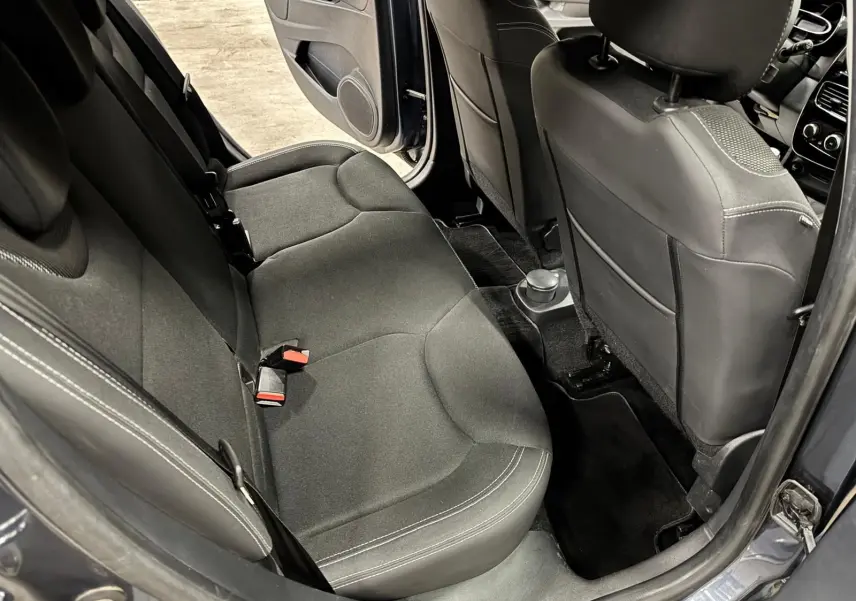 Vue intérieure arrière gauche de la Renault Clio IV gris foncé, montrant les sièges arrière en tissu noir et la porte ouverte.
