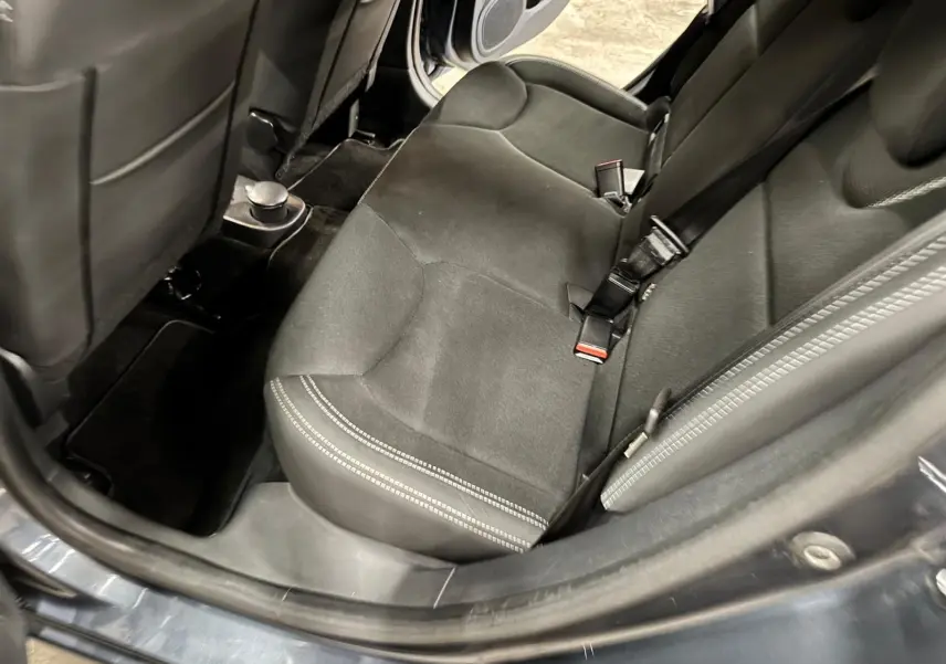 Vue intérieure arrière droite montrant la banquette en tissu noir et les ceintures de sécurité d'une Renault Clio IV gris foncé.