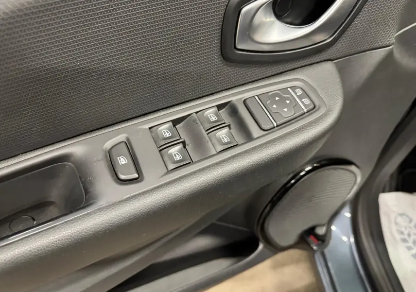 Gros plan sur la commande des vitres électriques côté conducteur de la Renault Clio IV gris foncé métal, porte ouverte.