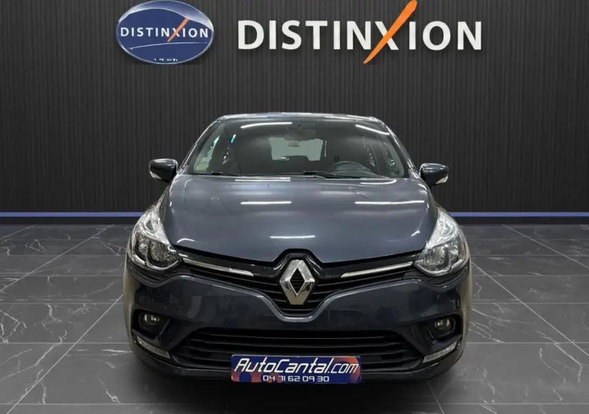 Vue avant d'une Renault Clio IV gris foncé métal, avec logo Renault bien visible et plaque AutoCantal.com.