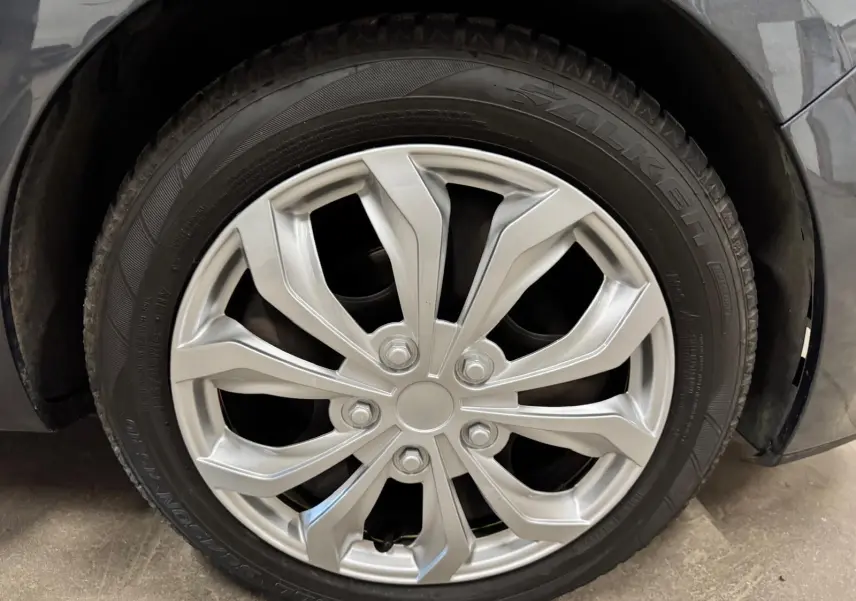 Gros plan sur la roue avant droite avec jante argentée de la Renault Clio IV gris foncé métallisé.