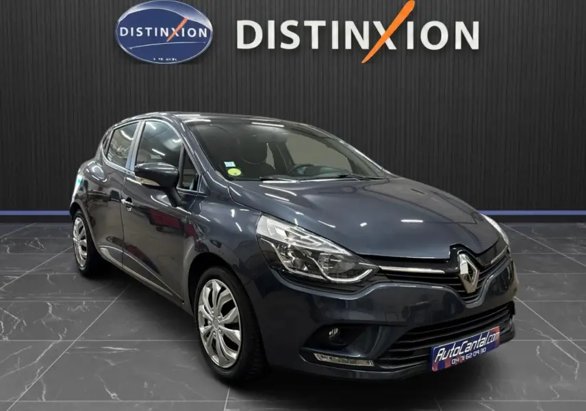 Renault Clio IV gris foncé métallisé vue 3/4 avant droit, avec phares LED et calandre chromée visible.