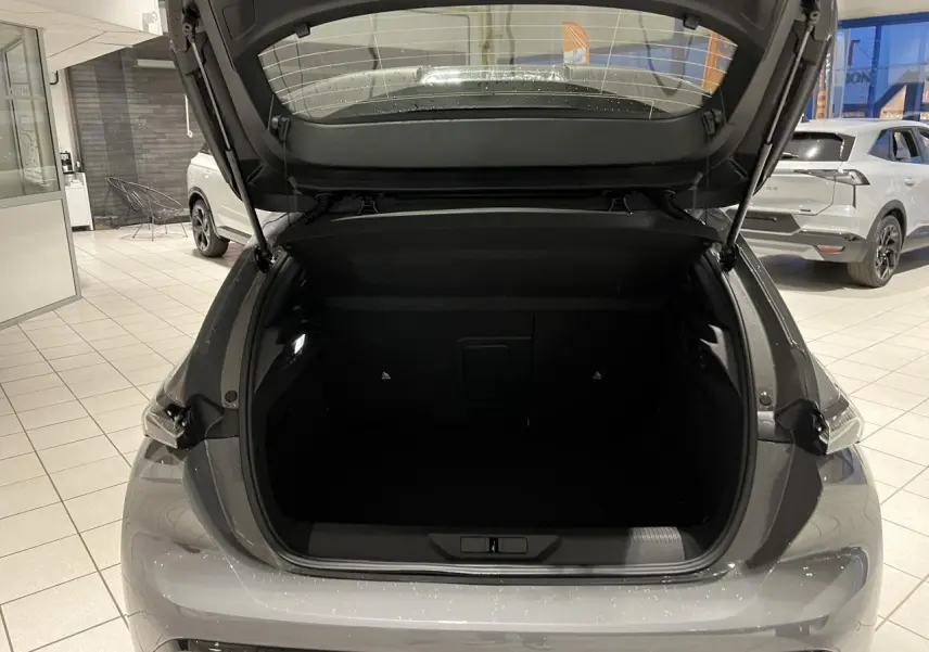 Coffre ouvert vu de l'arrière d'une Peugeot 308 gris selenium avec feux arrière à signature lumineuse griffe à griffe.