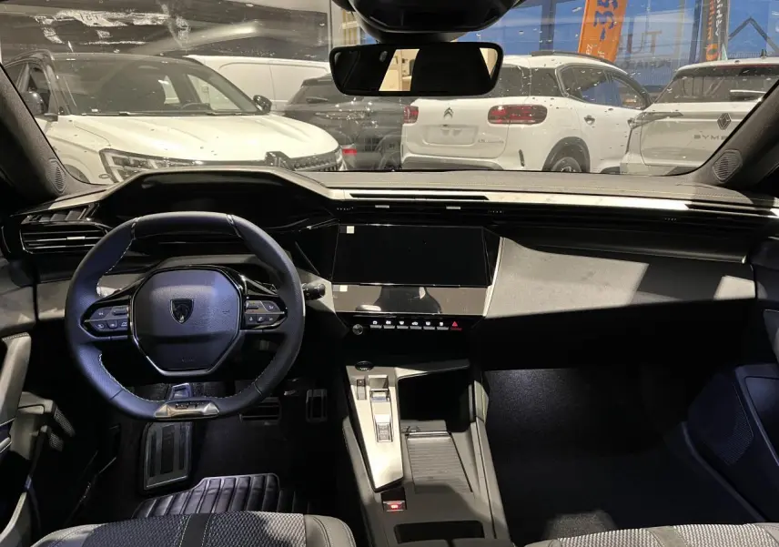 Vue intérieure avant du Peugeot 308 gris Selenium, volant cuir compact et console centrale moderne avec écran tactile noir.
