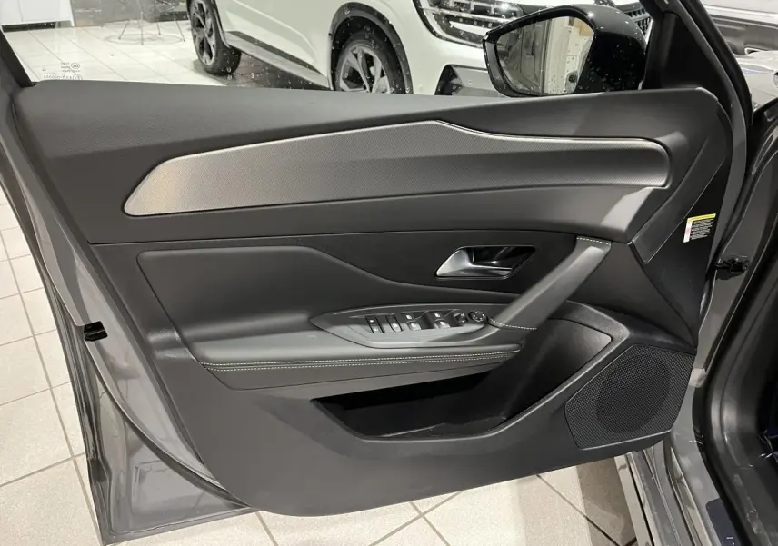 Porte avant gauche ouverte d'une Peugeot 308 GT gris selenium, avec garniture noire et inserts aluminium.