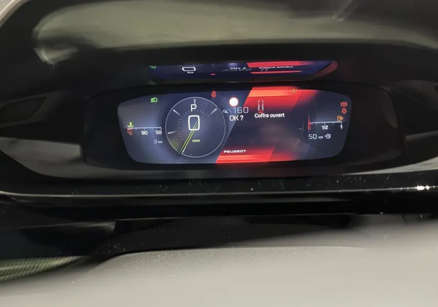 Tableau de bord numérique du Peugeot 308 GT 2024 affichant vitesse, jauge et alerte coffre ouvert.