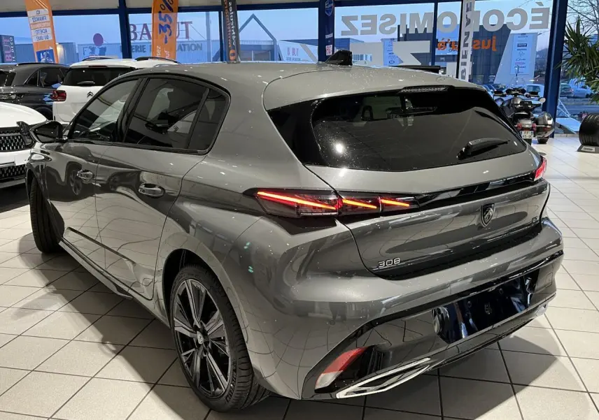 Peugeot 308 gris selenium vue 3/4 arrière droit en showroom, feux arrière LED griffés et jantes alliage 18 pouces.