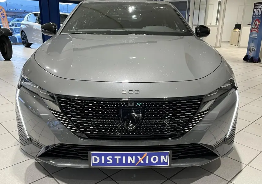 Vue avant d'une Peugeot 308 gris selenium avec calandre noire brillante et feux LED griffés en showroom.