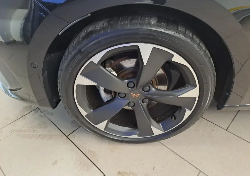 Gros plan sur la roue avant gauche d'une CUPRA Leon 2023 noire Minuit avec jante alliage noire et argentée au design distinctif.