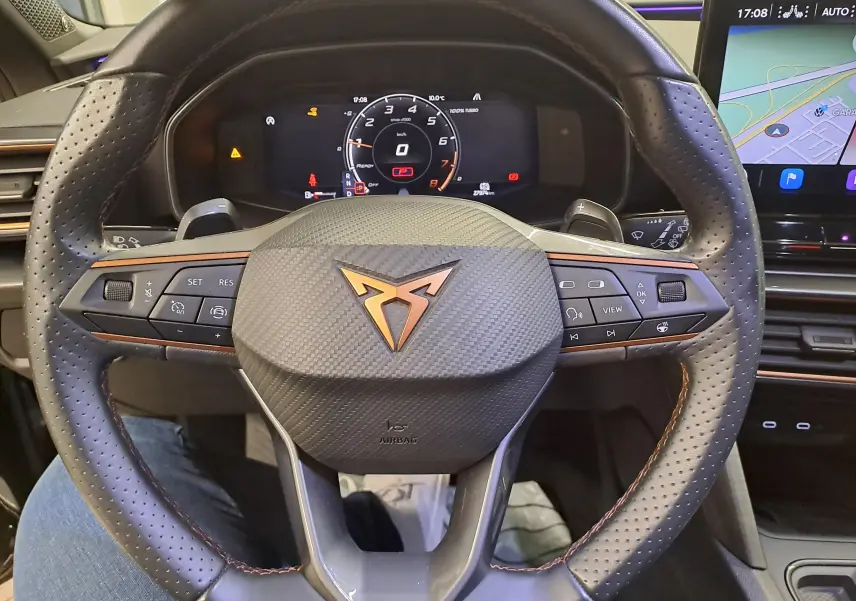 Vue rapprochée du volant en cuir perforé avec logo CUPRA cuivré et tableau de bord numérique du Leon 2023.