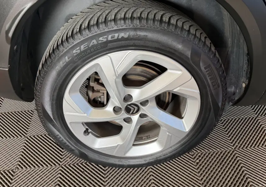 Gros plan sur la roue avant droite avec jante argentée et logo Citroën sur un C5 Aircross bleu.