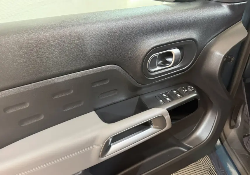 Gros plan sur la porte avant gauche bleu foncé du Citroën C5 Aircross avec commandes de vitres et poignée argentée.