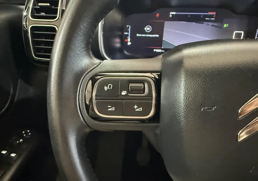 Gros plan sur le volant cuir noir de la Citroën C5 Aircross 2021, avec commandes multifonctions à gauche et tableau de bord numérique.