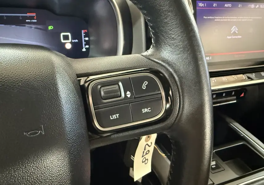 Gros plan sur le volant cuir multifonctions côté gauche du Citroën C5 Aircross avec tableau de bord numérique en arrière-plan.