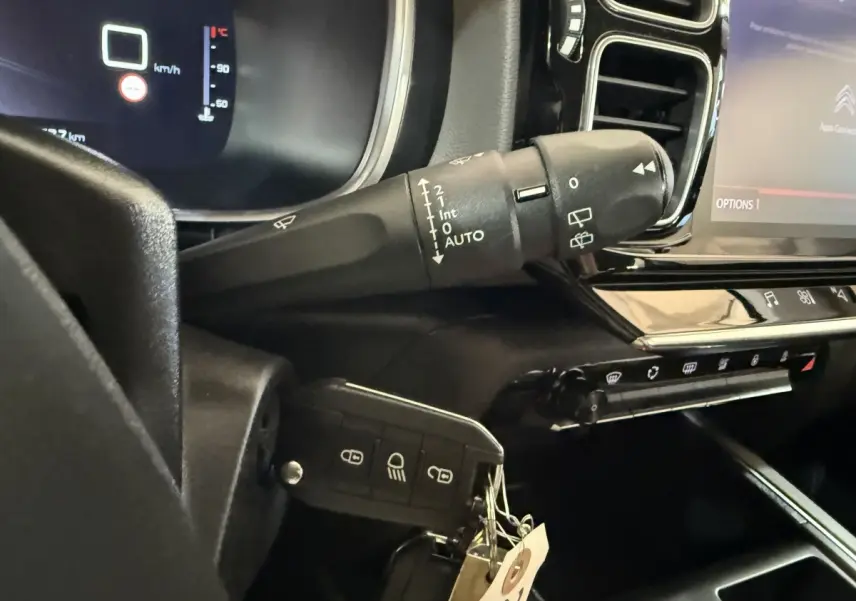 Gros plan sur la commande d'essuie-glace et la clé insérée dans le tableau de bord noir du Citroën C5 Aircross bleu.
