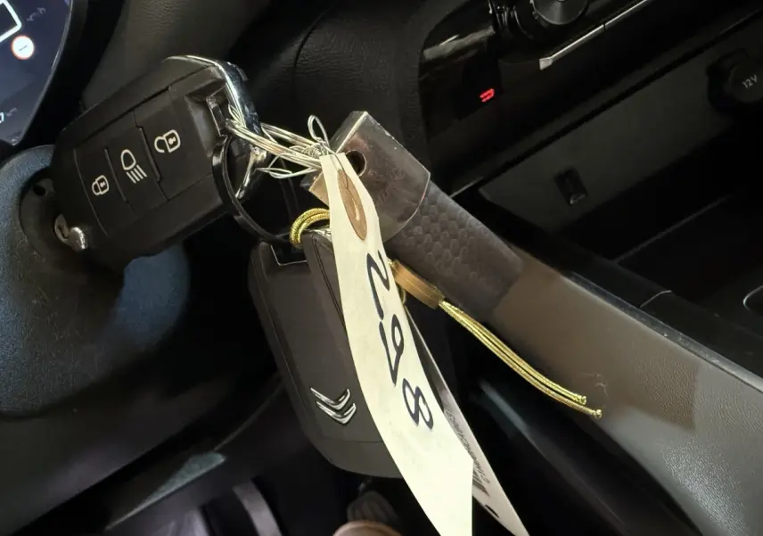 Gros plan sur la clé de contact Citroën insérée dans le contacteur, avec étiquette suspendue dans l’habitacle noir.