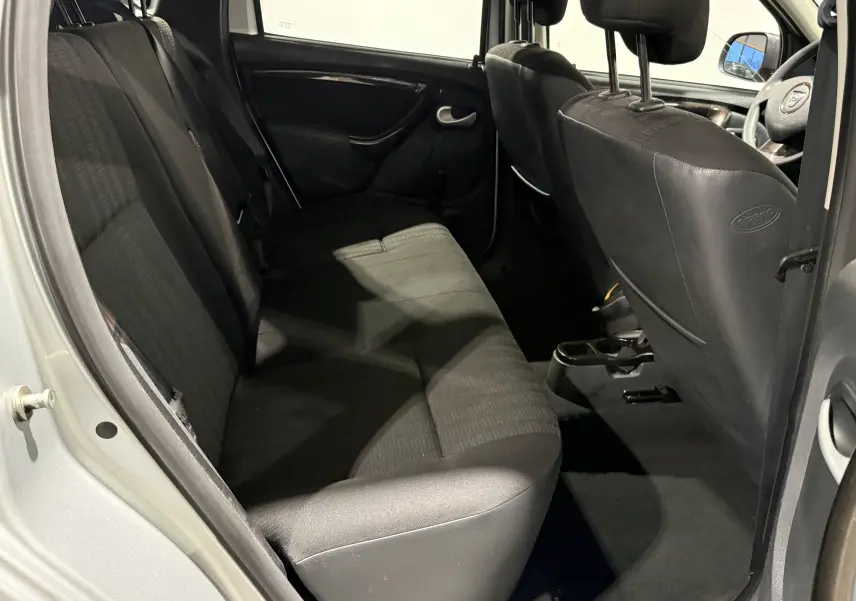 Vue intérieure côté droit sur la banquette arrière et les sièges avant noirs du Dacia Duster gris 2011.