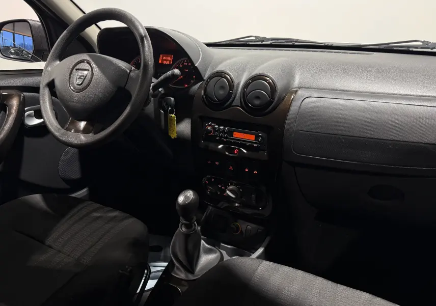Vue intérieure côté conducteur du tableau de bord et levier de vitesses manuel du Dacia Duster gris 2011.