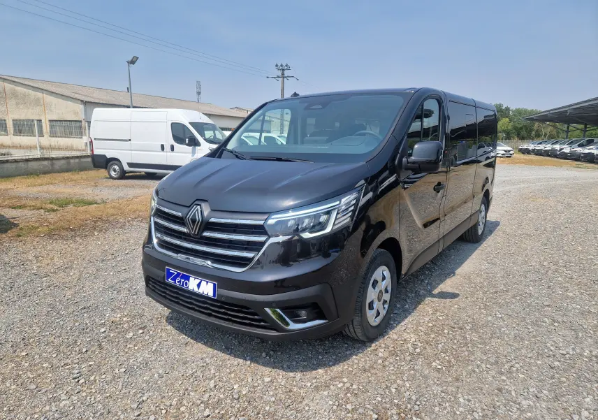 Renault Trafic Combi noir en 3/4 avant droit, avec calandre chromée et phares LED allumés, sur parking extérieur.