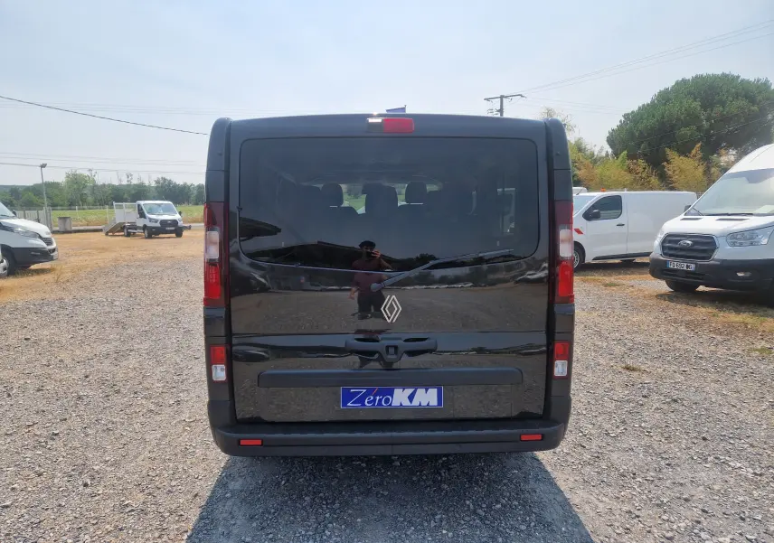 Vue arrière d'un Renault Trafic Combi noir 2026 avec vitre teintée et logo Renault visible au centre.
