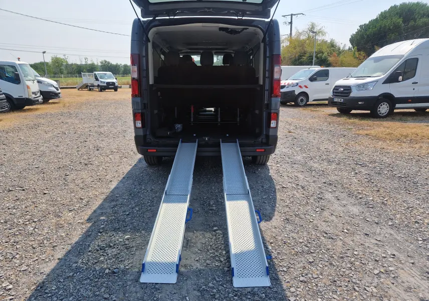 Vue arrière d’un Renault Trafic Combi noir 2026 avec rampes d’accès amovibles déployées au sol.