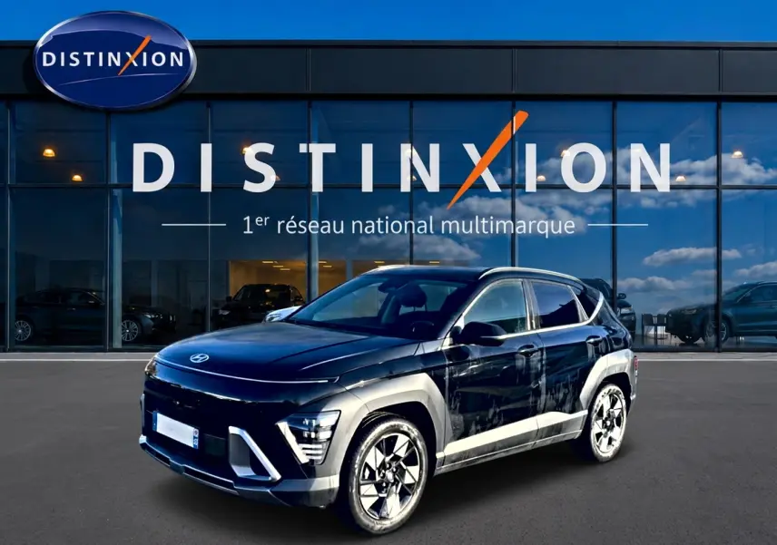 Hyundai Kona 2025 noir en 3/4 avant droit, avec jantes alliage et barres de toit visibles devant showroom Distinxion.