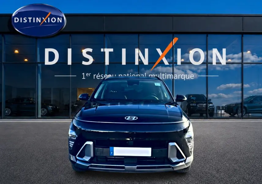 Vue frontale d'un Hyundai Kona noir 2025 avec calandre et phares LED distinctifs, devant une vitrine Distinxion.