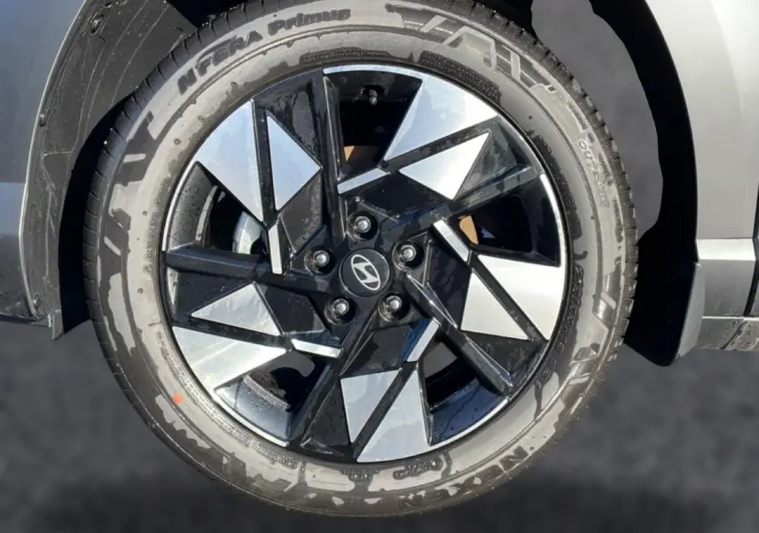 Gros plan sur la jante alliage 18 pouces noire et argentée du Hyundai Kona 2025 noir, avec pneu Nexen visible.