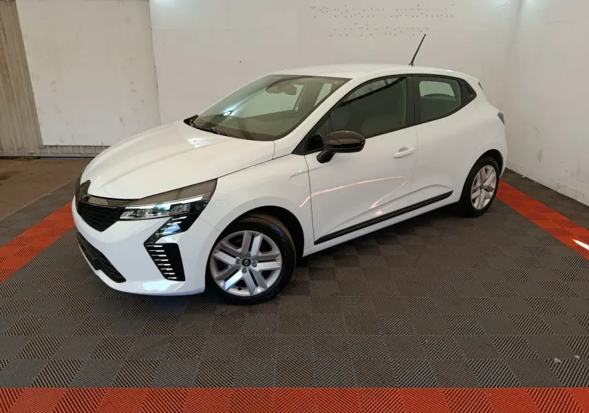 Renault Clio blanche vue 3/4 avant droit en intérieur, avec phares LED et rétroviseurs noirs contrastants.