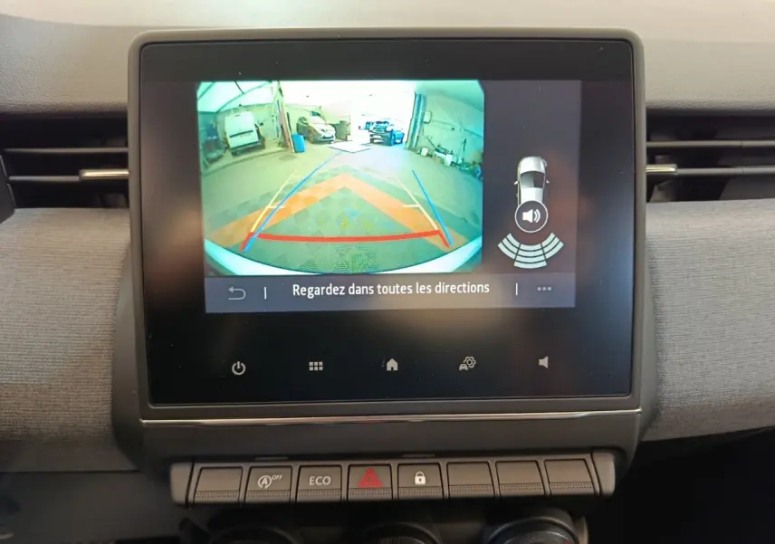 Écran tactile central montrant la caméra de recul et l’aide au stationnement du tableau de bord d’une Renault Clio blanche.