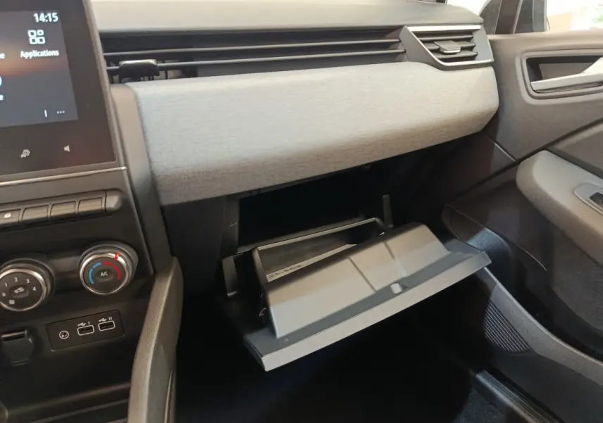 Intérieur de la Renault Clio 2024, vue du côté passager avec boîte à gants ouverte et tableau de bord gris clair.