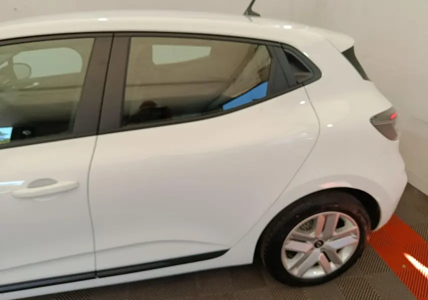 Vue latérale côté gauche d'une Renault Clio blanche 2024, mettant en valeur la porte arrière et la jante alliage.